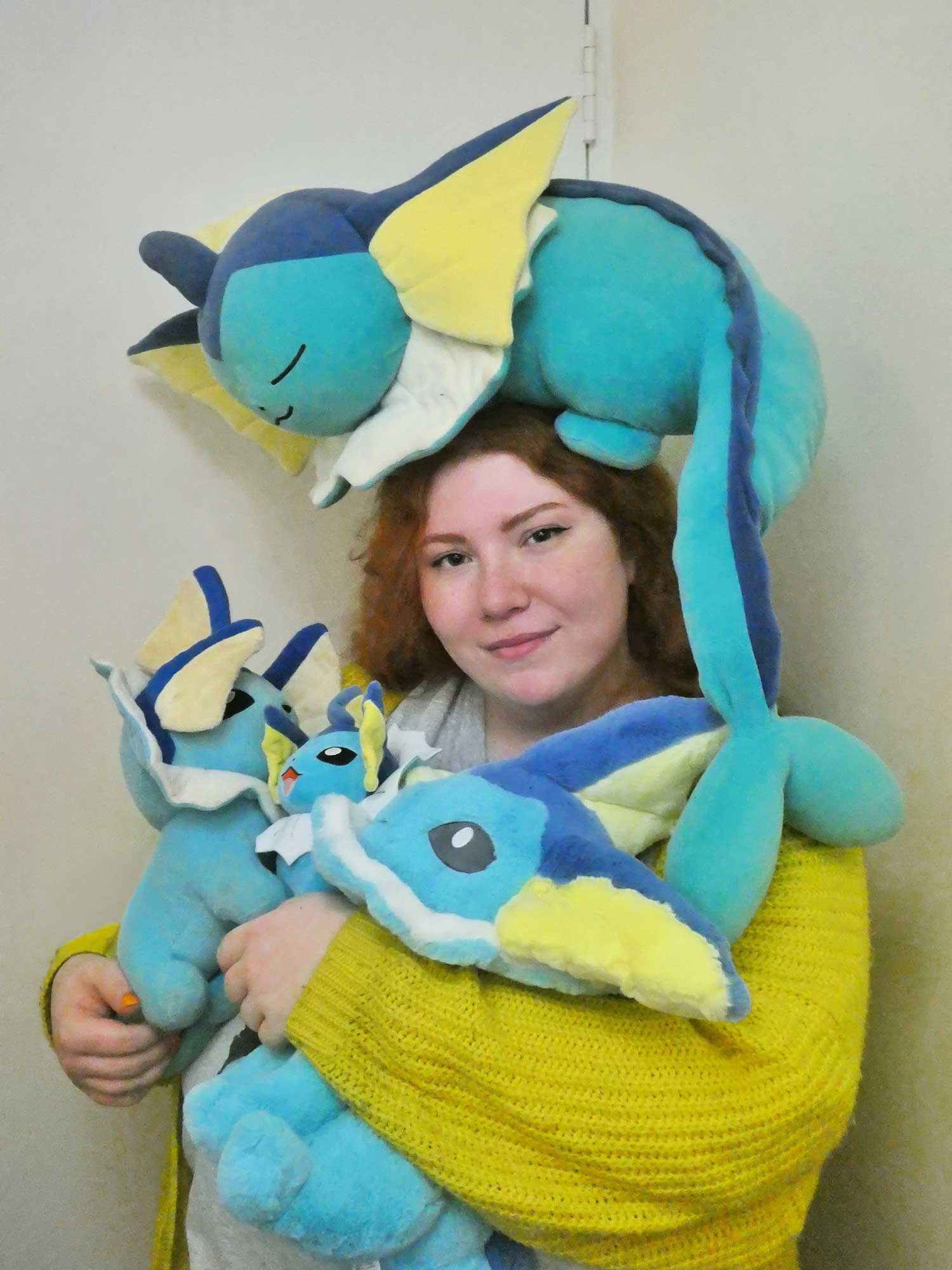 A person surrounded by multiple plush Vaporeon toys.