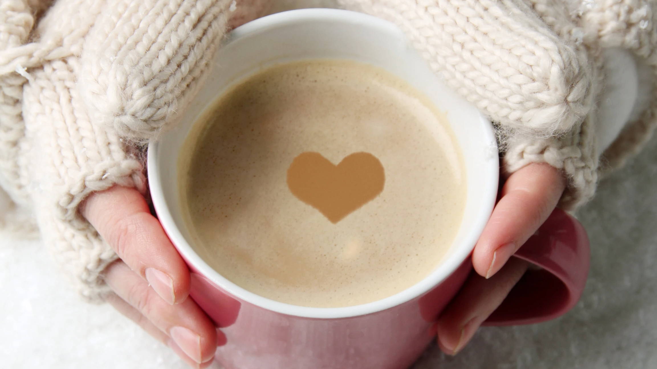 Woman's hands in winter gloves holding a cup filled with a hot energy drink