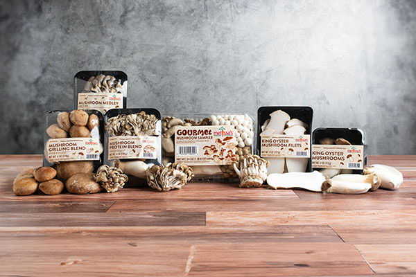 Various packaged mushrooms and nuts on a wooden surface.