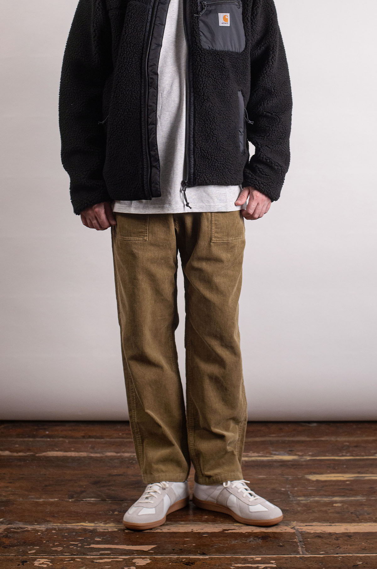 Person wearing a black jacket, white shirt, khaki pants, and white shoes.