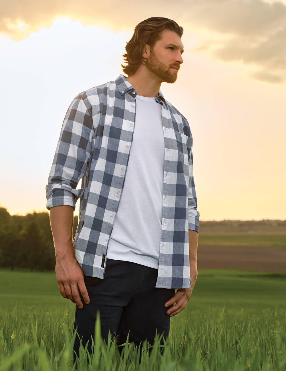 Tall man standing in a field wearing a linen plaid shirt by American Tall.