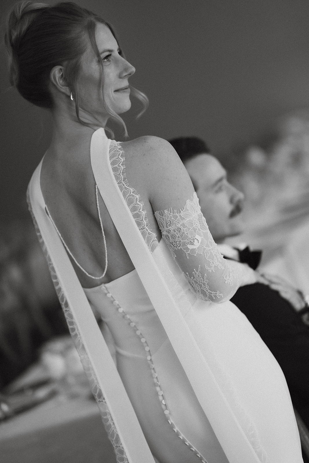 A woman in a wedding dress sits beside a man.