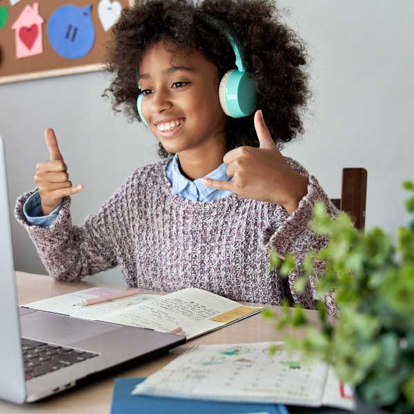 A child doing a webcam on a laptop with schoolwork in front of them