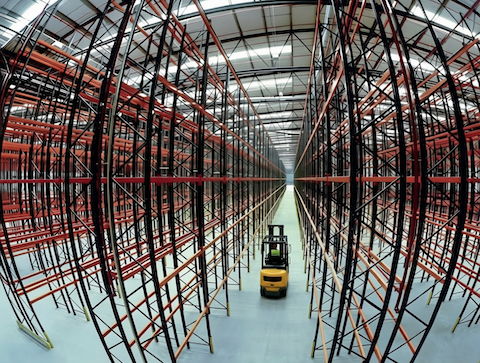 forklift traveling down aisle of warehouse