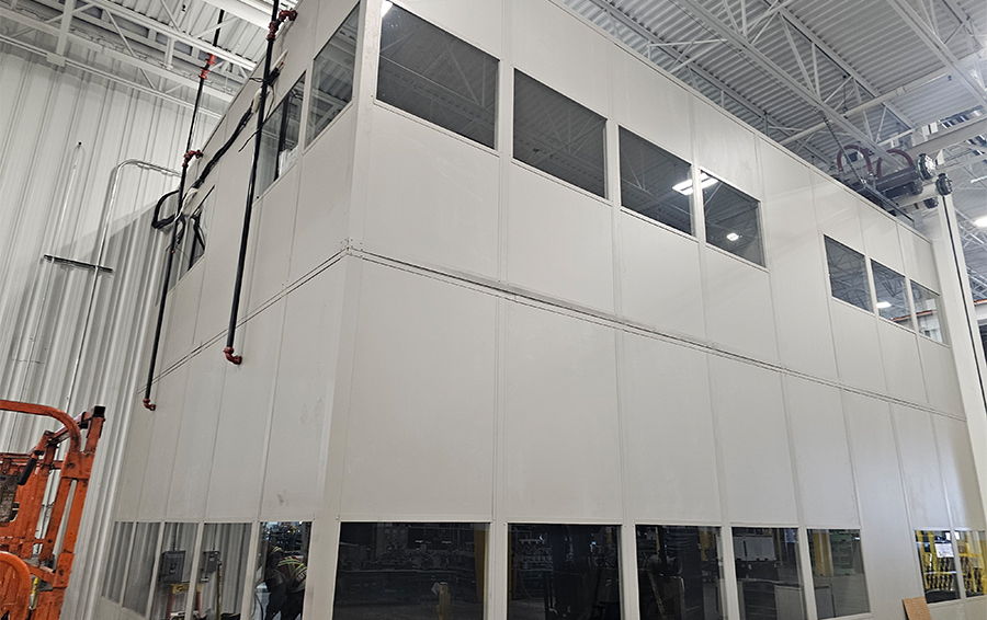 A large white structure with windows, situated in an industrial space.