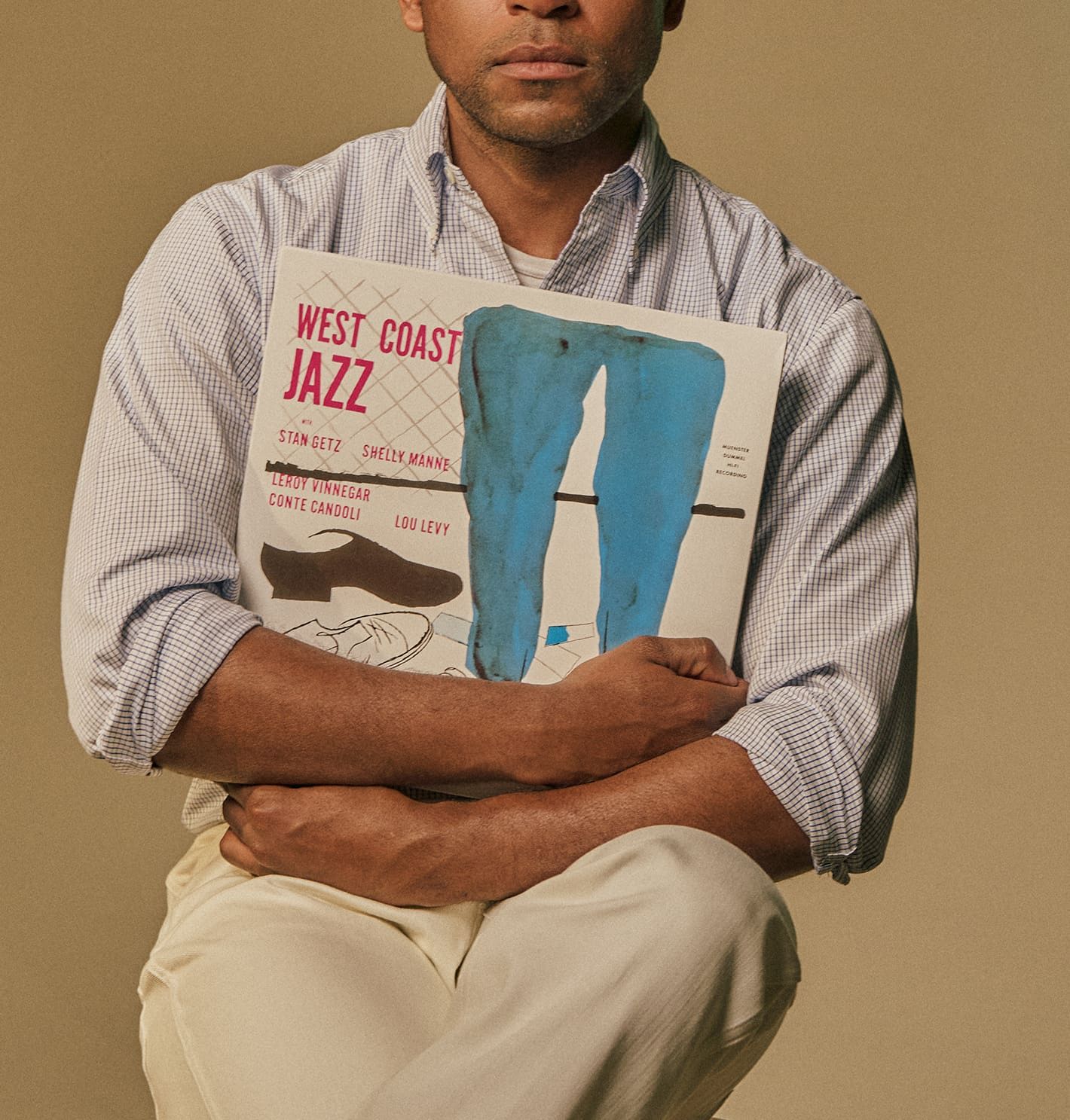 Person holding a jazz record album, seated against a neutral background.