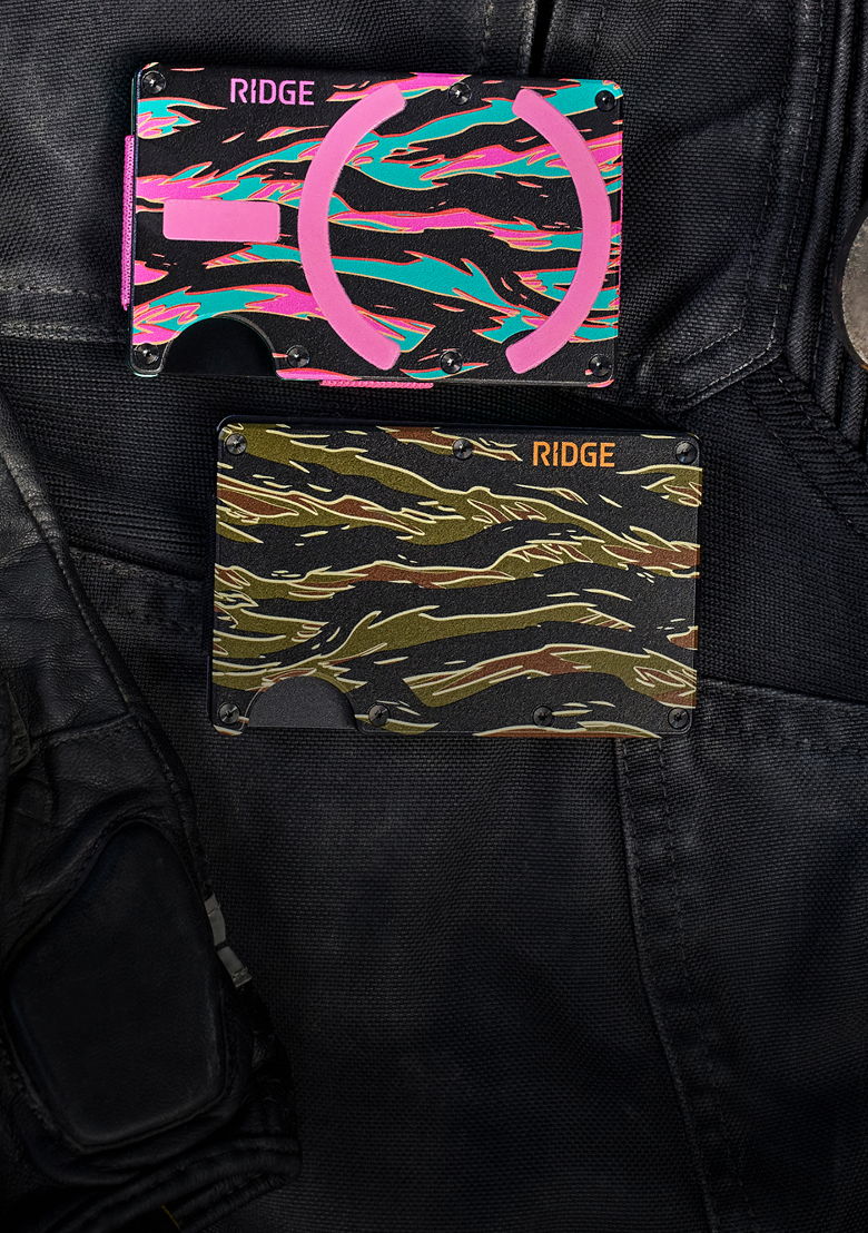 Two colorful Ridge wallets on a dark fabric background.