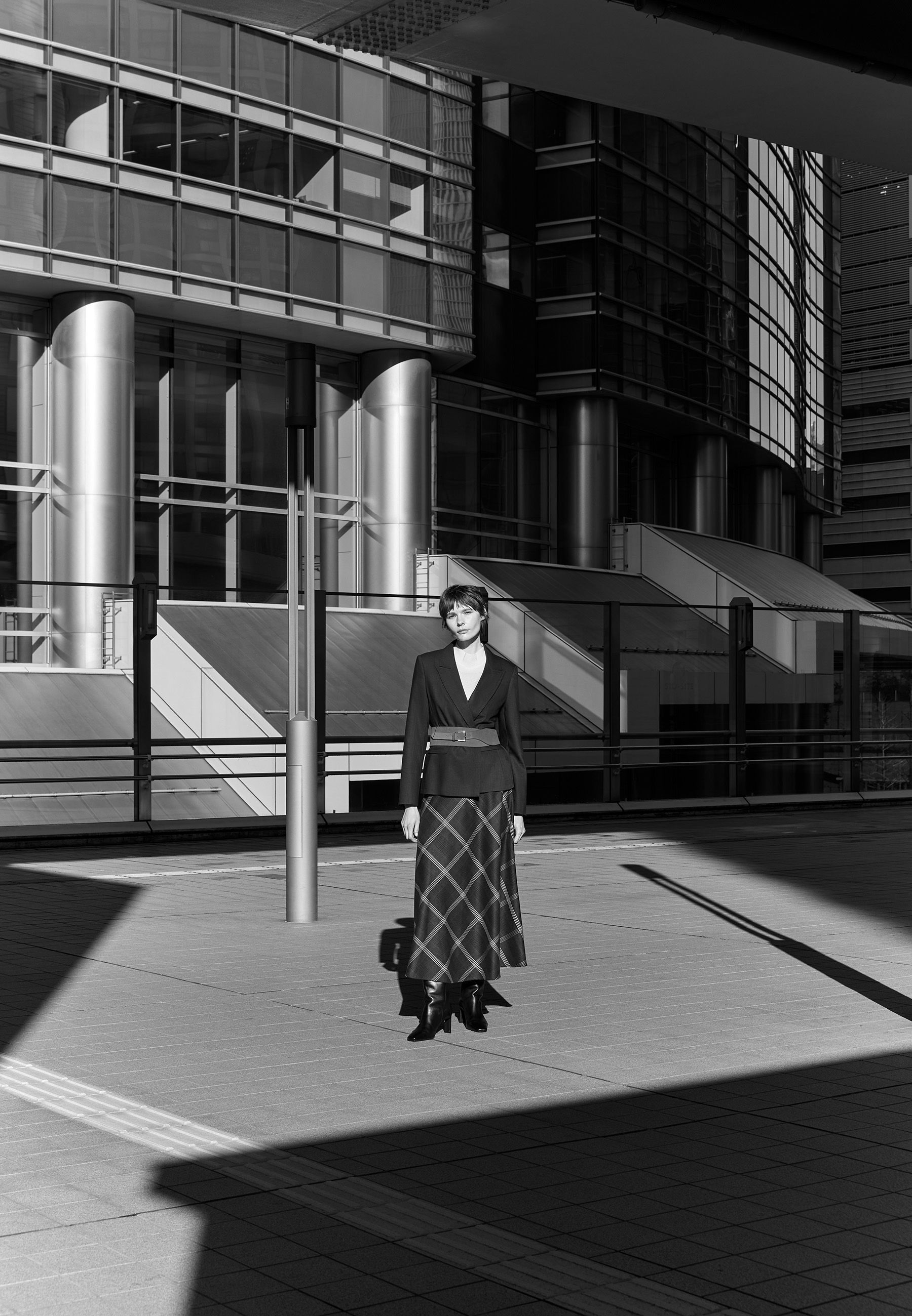 A person in a stylish outfit stands in a modern urban setting.