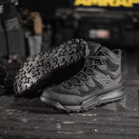 Black tactical boots displayed on a dark surface with equipment in background.