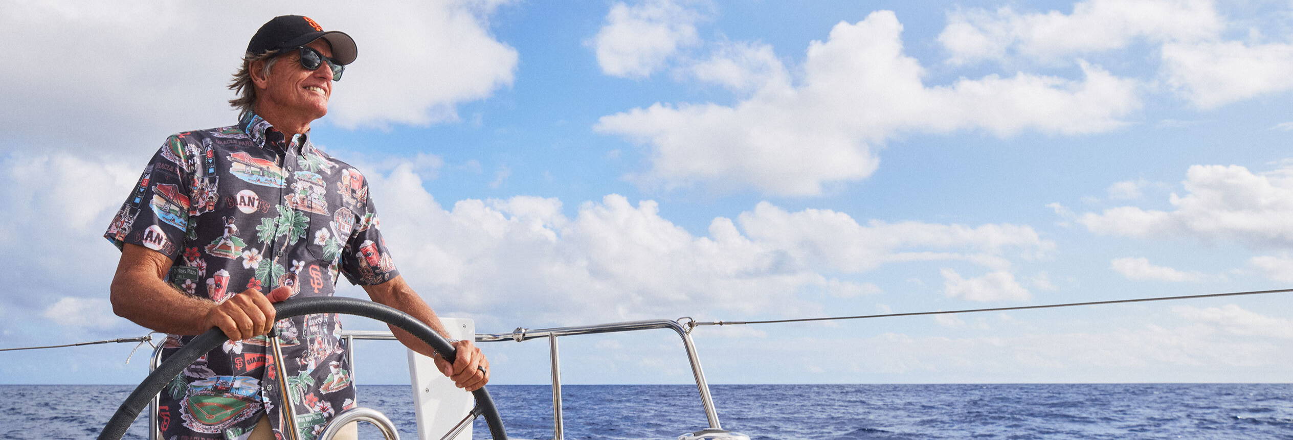A person steering a boat on the ocean under a cloudy sky.