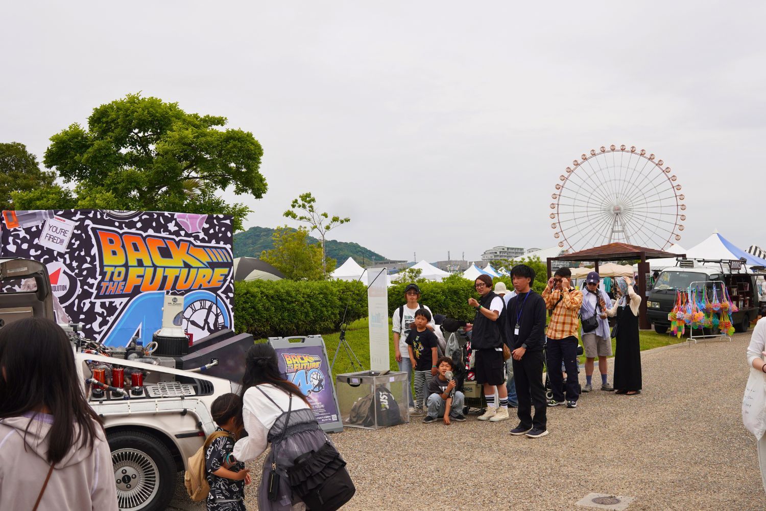 People at an outdoor event with a ferris wheel in the background.