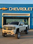 Front three-quarter Brianna's lifted white Chevy Silverado at Chevrolet dealership at golden hour photo 1