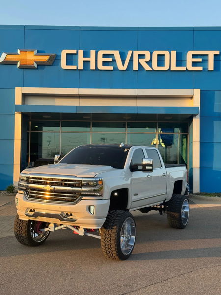 Front three-quarter Brianna's lifted white Chevy Silverado at Chevrolet dealership at golden hour photo 1