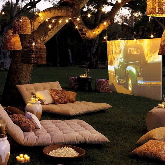 Outdoor cinema setting with LED festoons and candles on the floor.