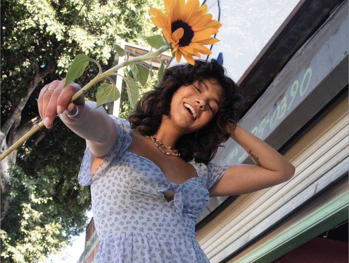 Trixxi Las Fotos Class C.E.O project photoshoot, girl in blue romper holding a sunflower.