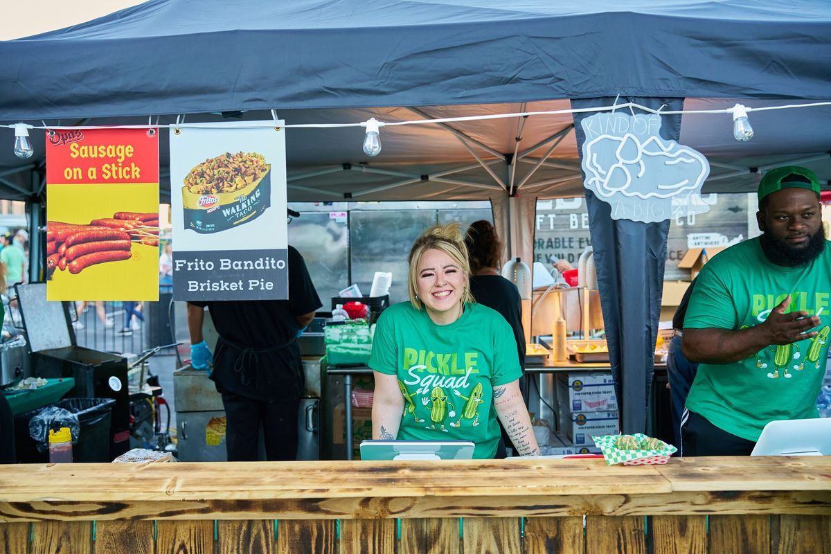 Food stall with two vendors, one smiling, selling items.