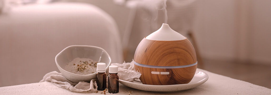 A wooden essential oil diffuser with oil bottles and herbs.