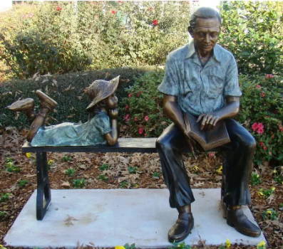 Grandpa & granddaughter sitting on a park bench reading a book statue