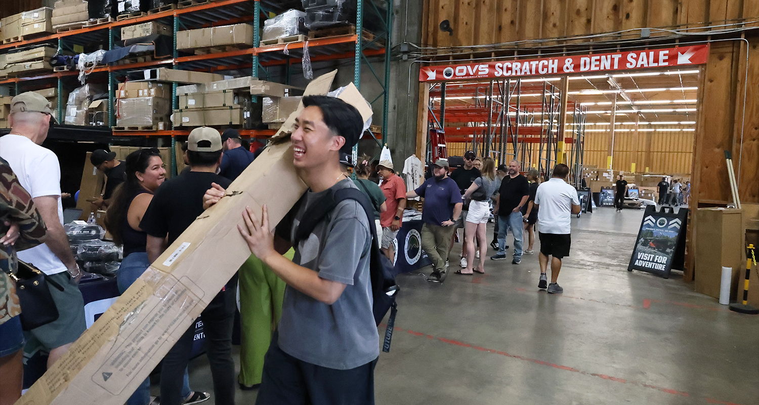 A person carrying a large piece of wood in a crowded store.