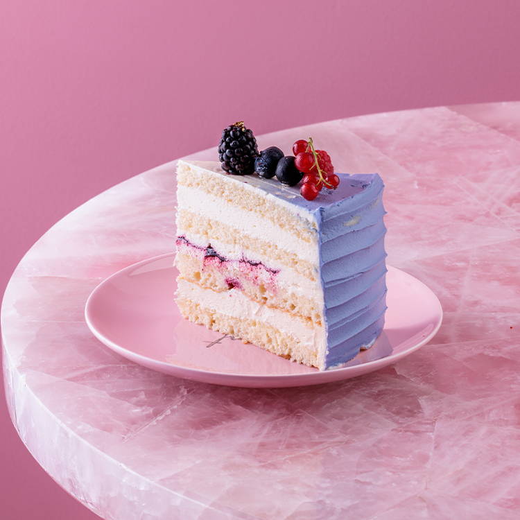 Mixed berry cake slice with lilac icing and fresh fruits