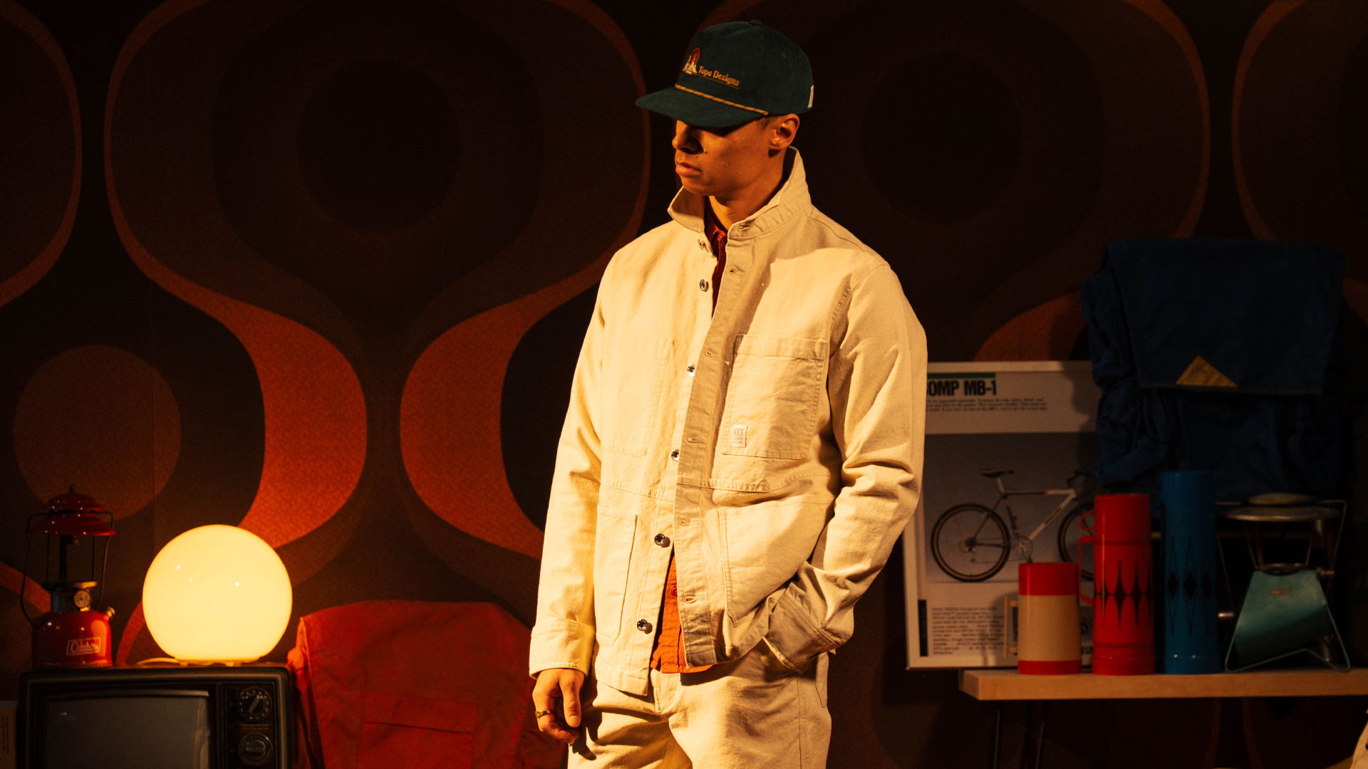 A person in a stylish outfit stands against a retro background.