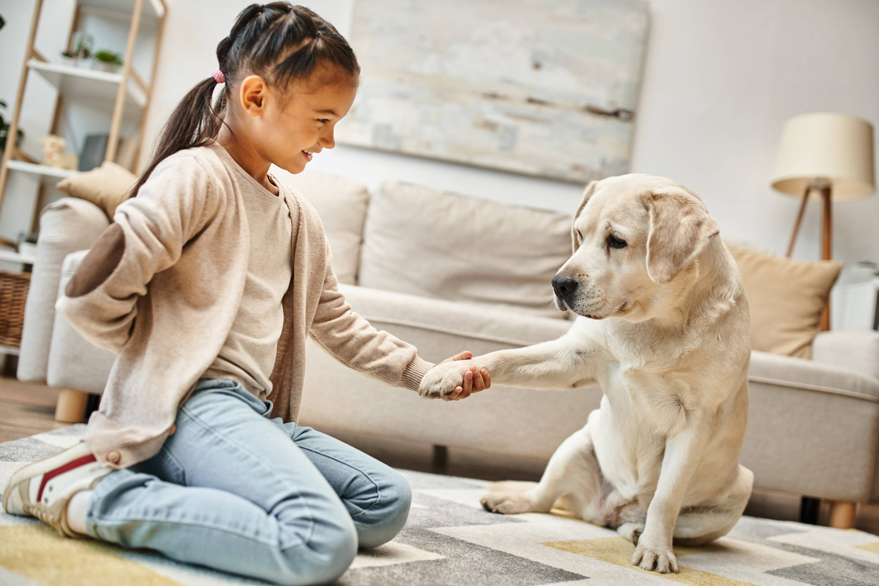 Child playing with dog in living room