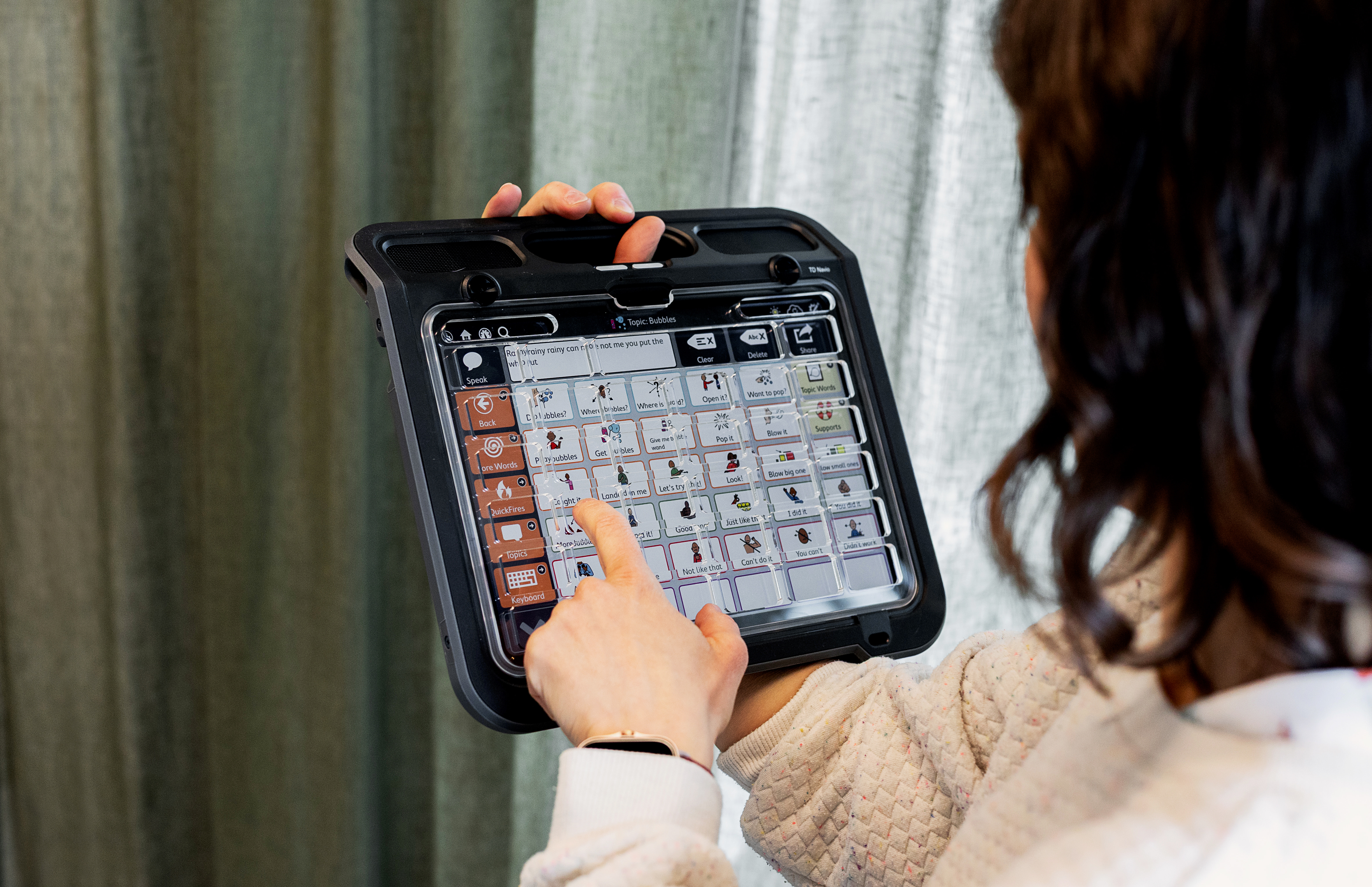 Woman using touch access method to select a picture communication symbol (PCS) on a TD Navio speech generating device.