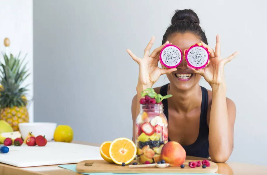 Woman smiling with a tropical fruit salad, being playful covering her eyes with dragon fruit|5 Ways To Boost Your Gut Health and Immune System |Gut Health and Your Immune System