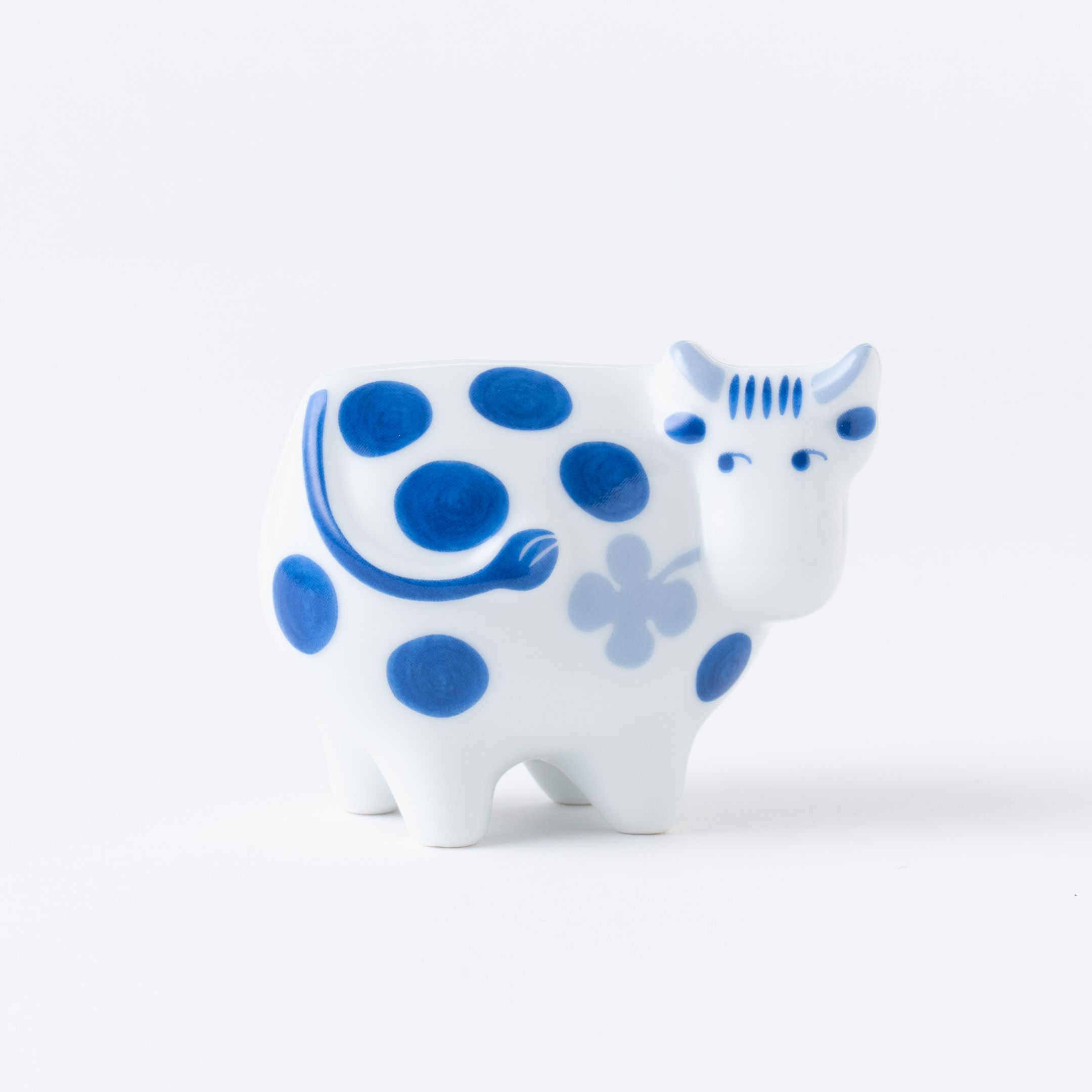 A decorative white cow figurine with blue spots and a flower design.