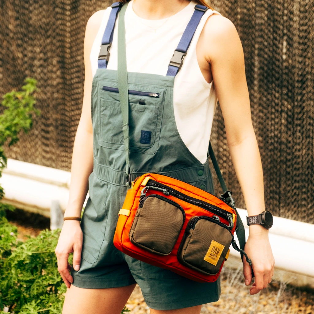 Person wearing a green outfit with an orange and brown crossbody bag.