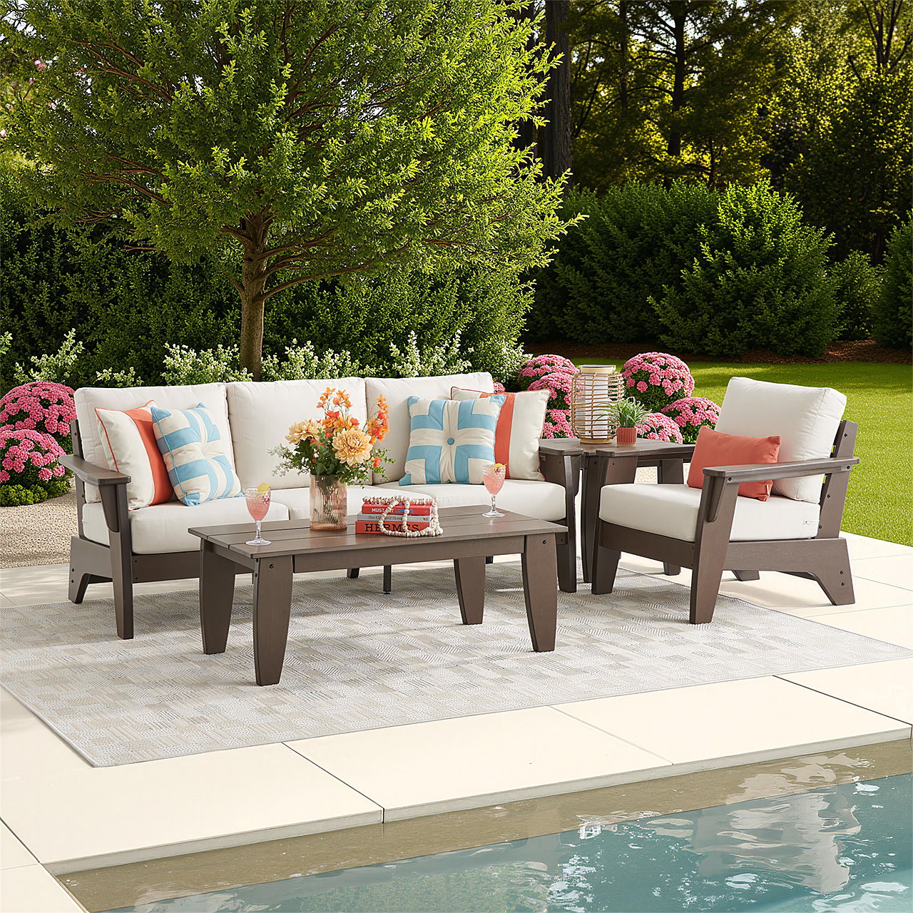 Outdoor seating arrangement by a pool with decorative pillows and flowers.