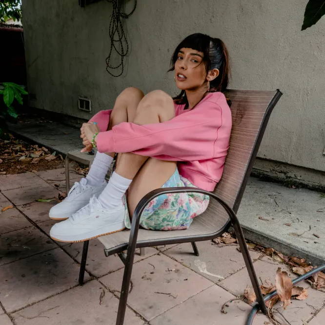 woman in reebok shoes on chair in backyard