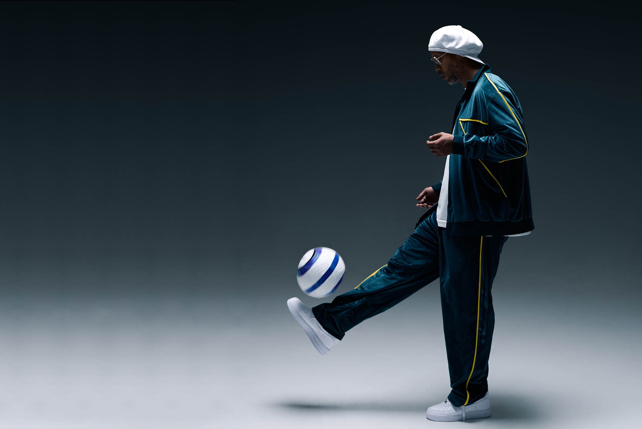 Ronaldinho in sportswear juggling a soccer ball against a dark background.