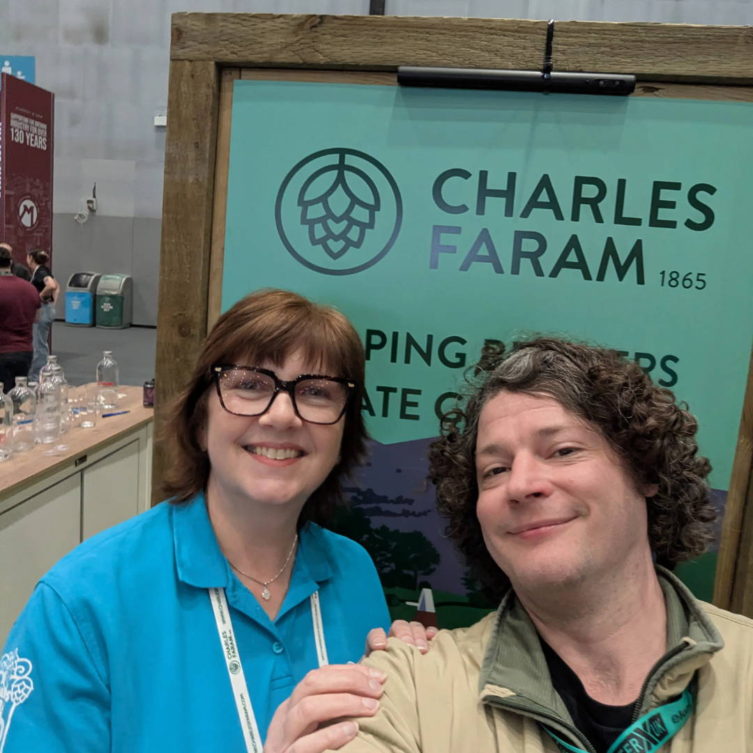 Dan and friend smiling in front of a sign for Charles Faram.