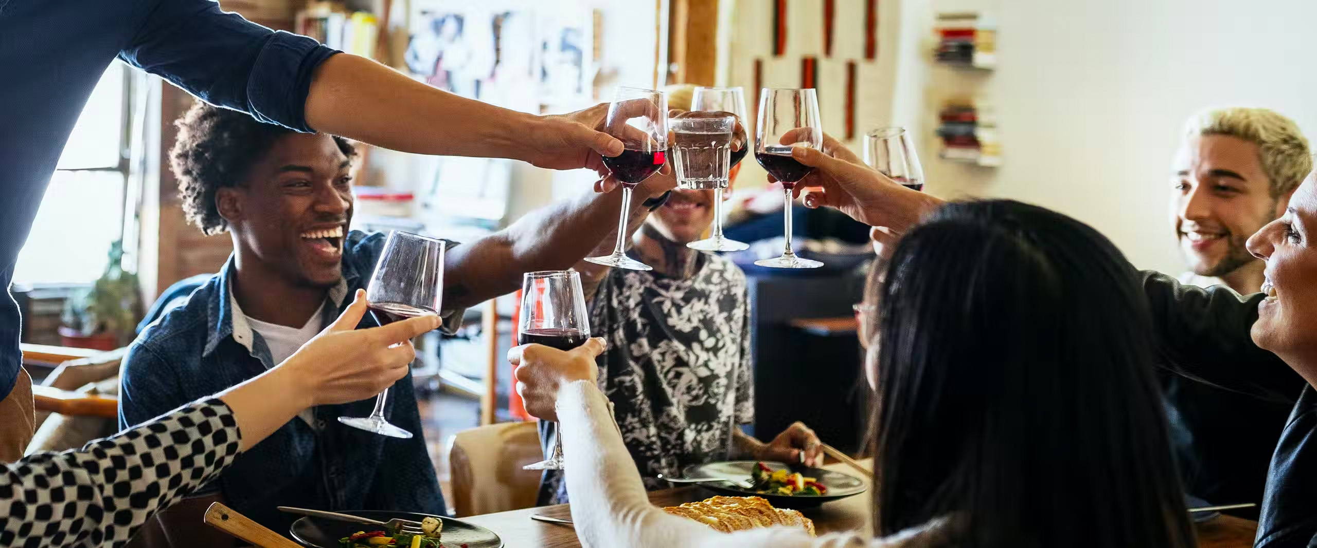 Group of 20-something friends, smiling and sharing a wine toast. Cheers!