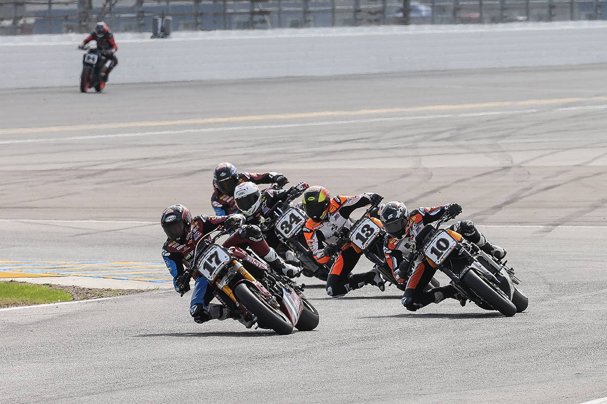 A dynamic racing scene depicting a group of motorcyclists leaning into a sharp turn at Daytona International Speedway, showcasing intense competition and speed.