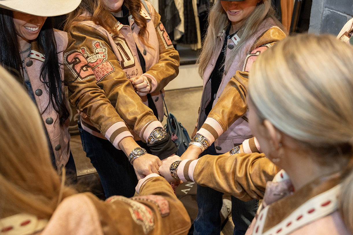 A group of the 2026 Class of Cowgirl 30 Under 30 admiring their bracelets and new jackets.