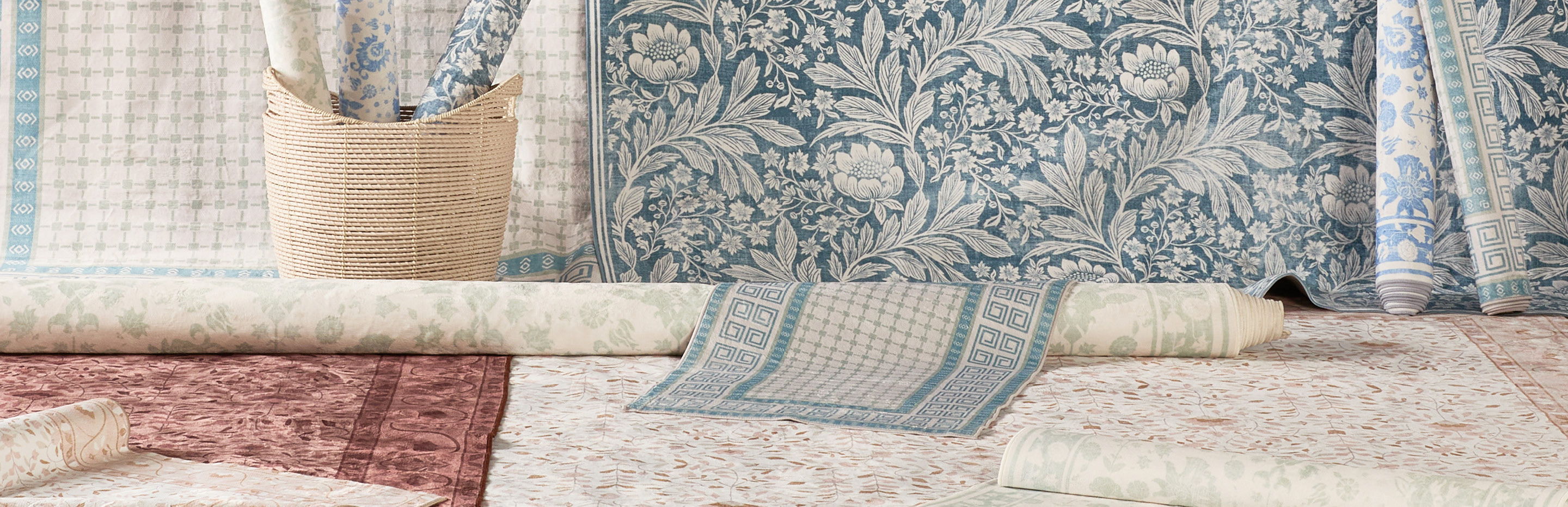 Rolled and laid out patterned fabrics with a woven basket in the background.