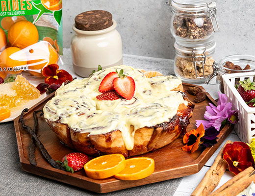 A delicious dessert topped with strawberries and surrounded by fruits and flowers.