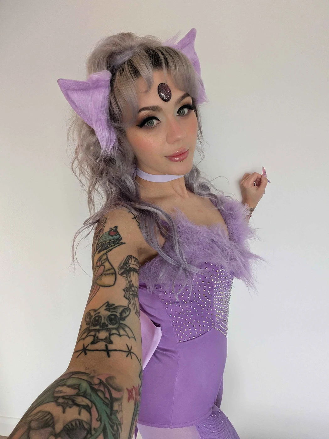 Person in purple costume with cat ears and tattoos posing for a selfie.