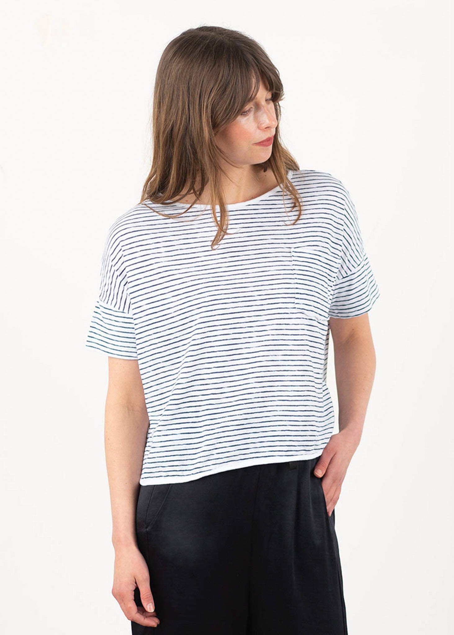 A model wearing a black and white striped boxy, shortsleeved t shirt.