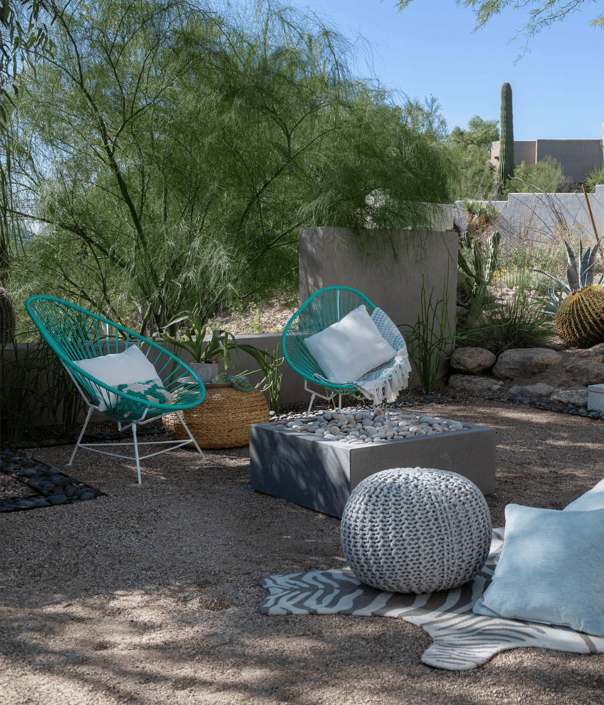 Modern lounge chairs around a fire pit in a desert backyard space.