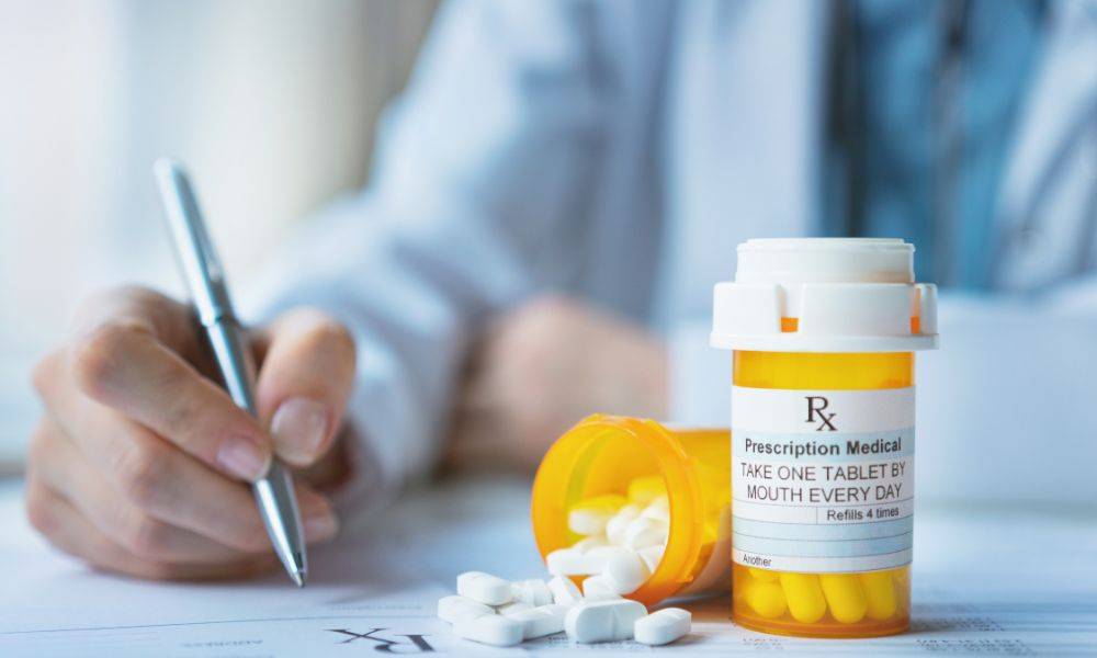 Doctor prescribing medicine with bottle of medication nearby