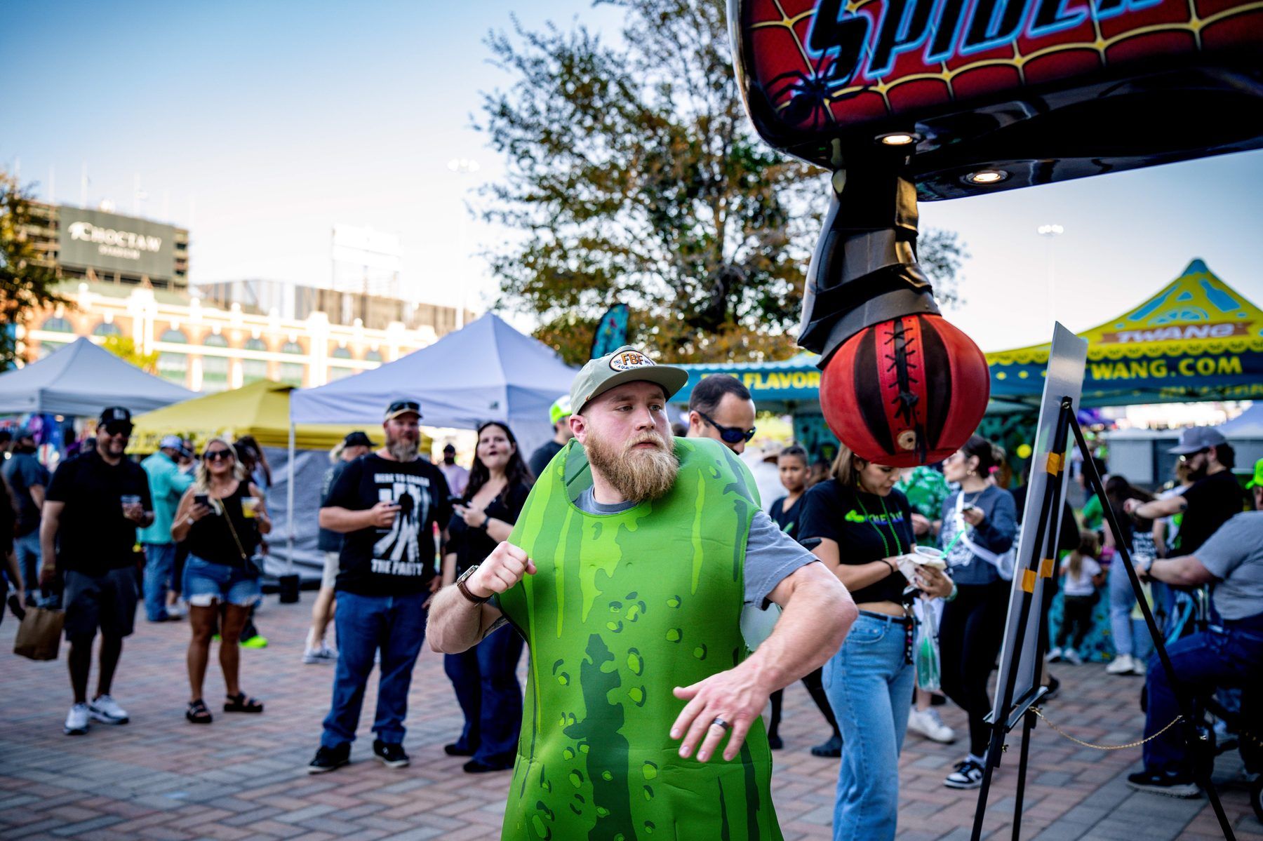 Guest in pickle costume hitting the Spider-Man punching bag activation at The Big Dill Arlington Texas 2025.