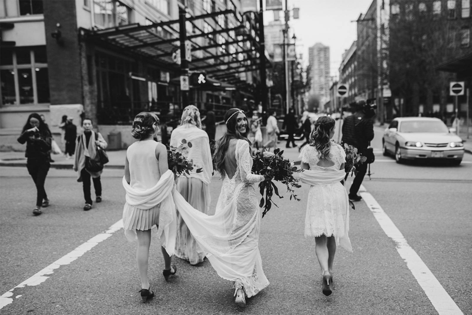 Bride smiling crossing street with guests