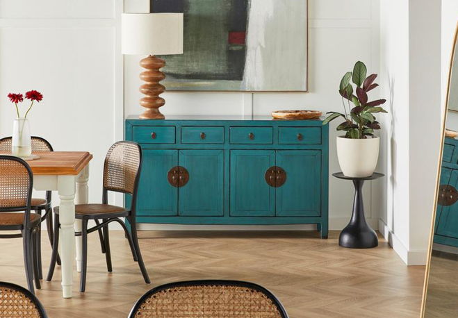 A stylish dining area with teal cabinet, wooden table, and decorative plants.