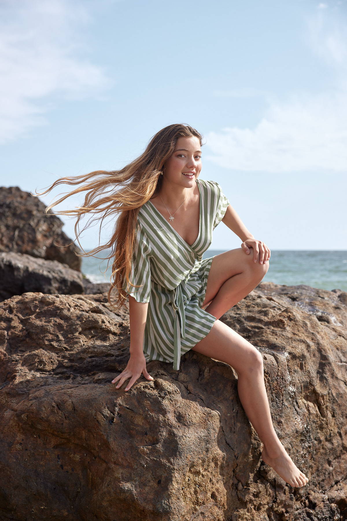 Trixxi sun-kissed summer, girl at oceanside at rocks in sage white stripe romper.