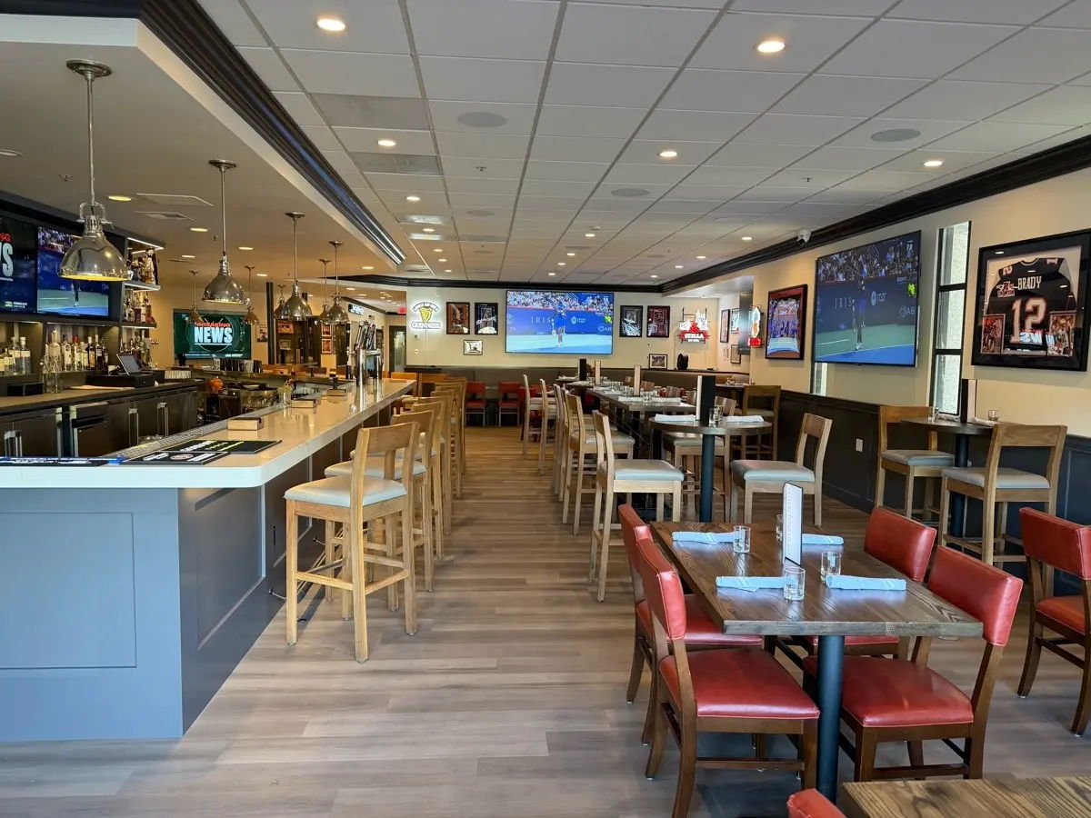 Interior of a modern restaurant with tables, chairs, and large screens.