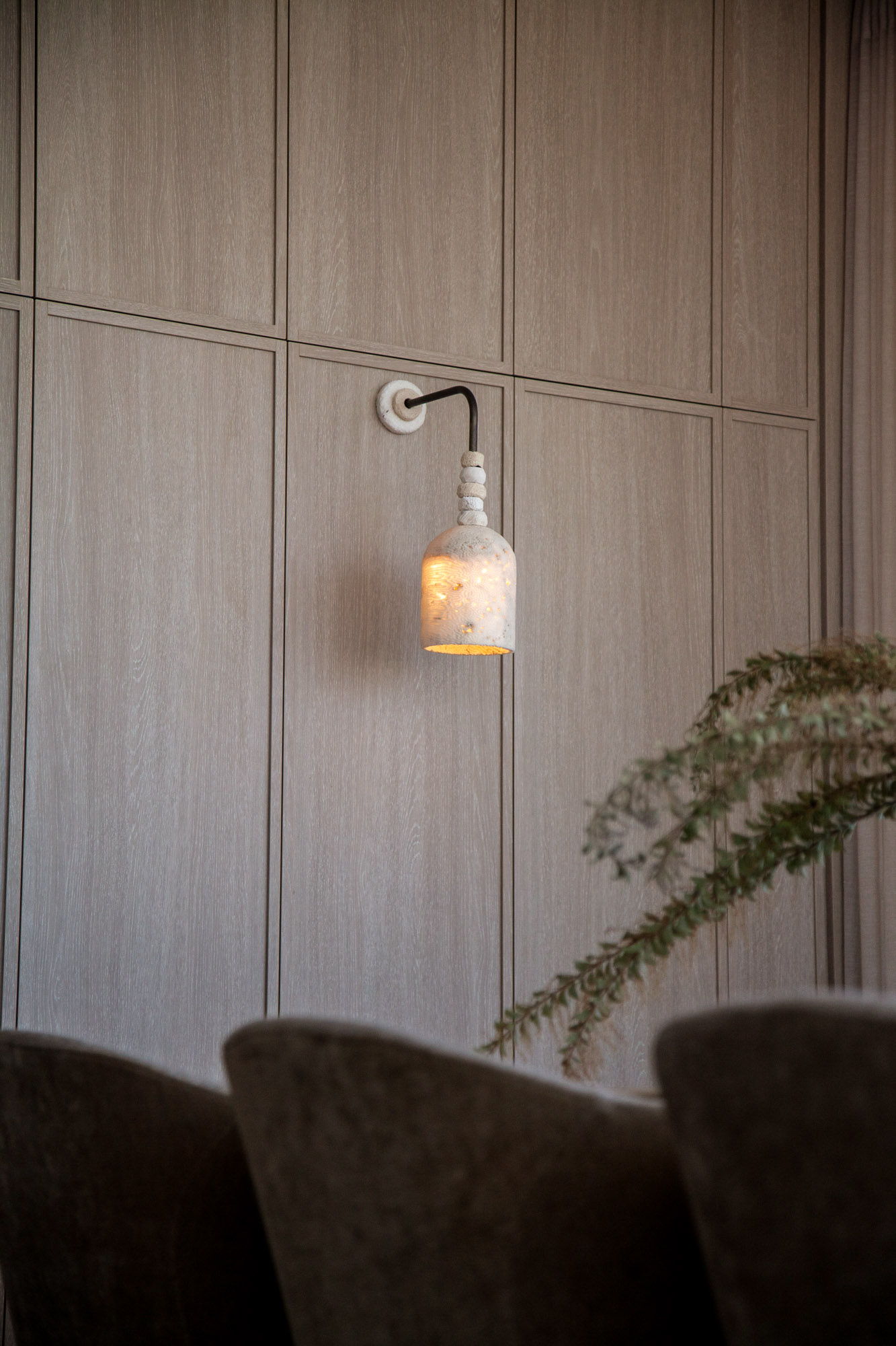 Fossil coral arc dome wall light next to a textured wooden panel.