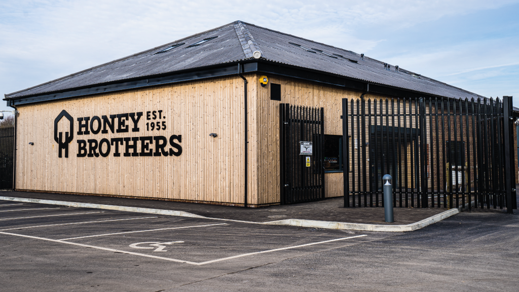 Exterior of Honey Brothers building with modern design and parking lot.